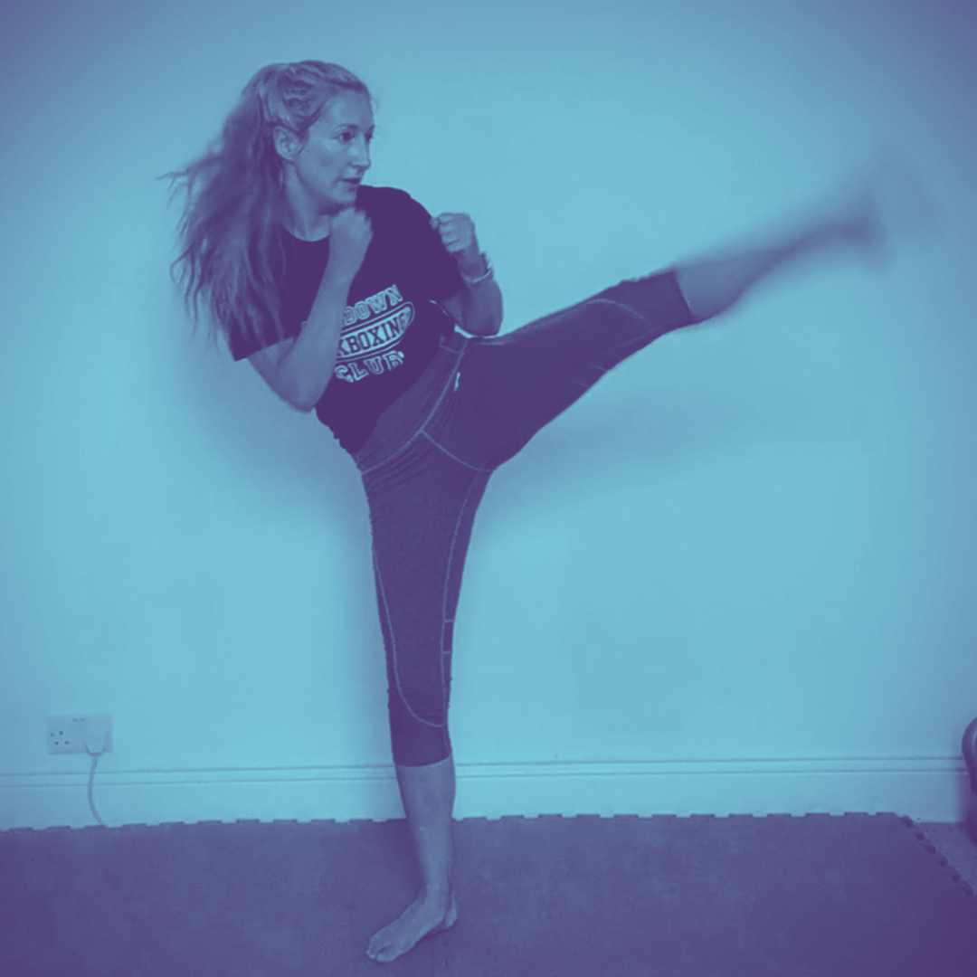 Blue tinted image of woman performing a high turning kick.